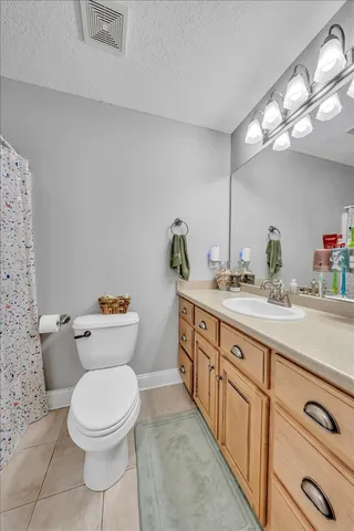 a bathroom with a granite countertop toilet sink and mirror