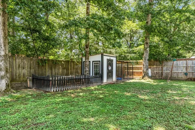 a backyard of a house with plants and large tree