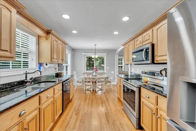 a kitchen with granite countertop lots of counter top space a sink stainless steel appliances and cabinets