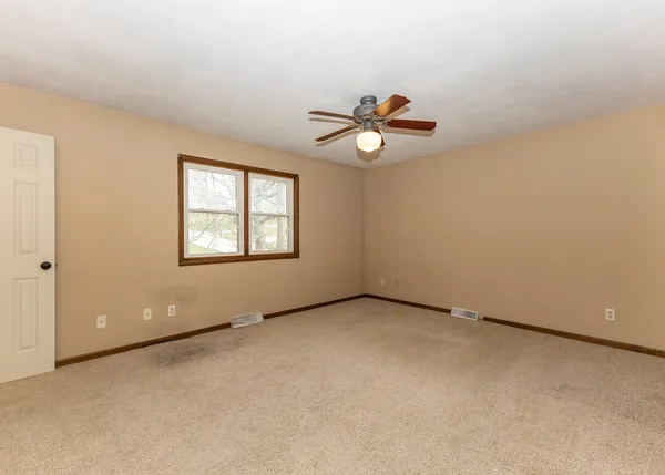 an empty room with windows and ceiling fan