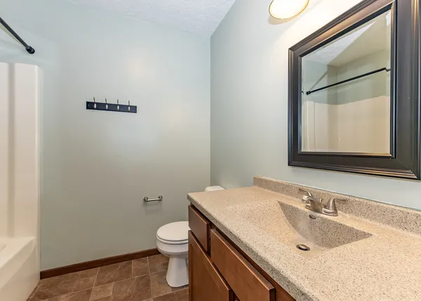 a bathroom with a granite countertop sink toilet and mirror