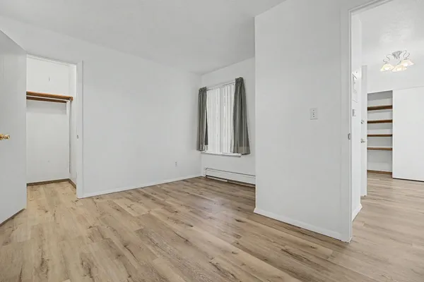 an empty room with wooden floor and cabinet