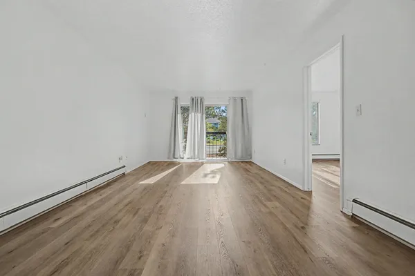 an empty room with wooden floor and windows