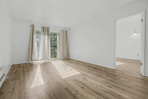 an empty room with wooden floor and windows