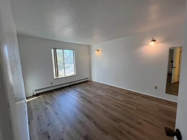 an empty room with wooden floor and windows