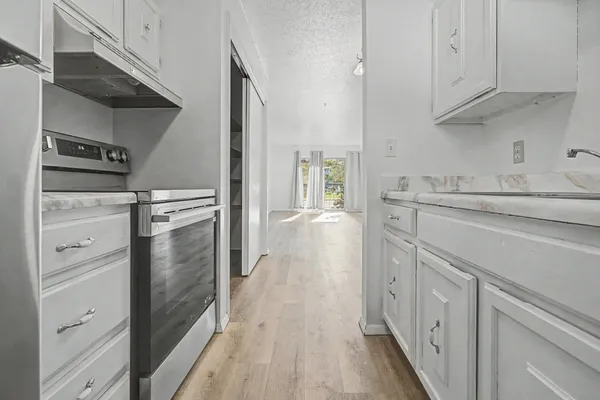 a kitchen with white cabinets and refrigerator