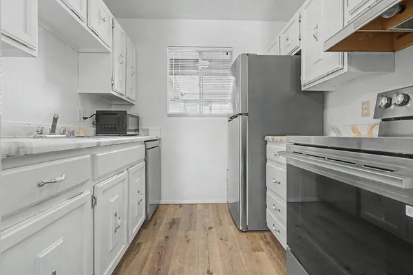 a kitchen with cabinets appliances and a wooden floor