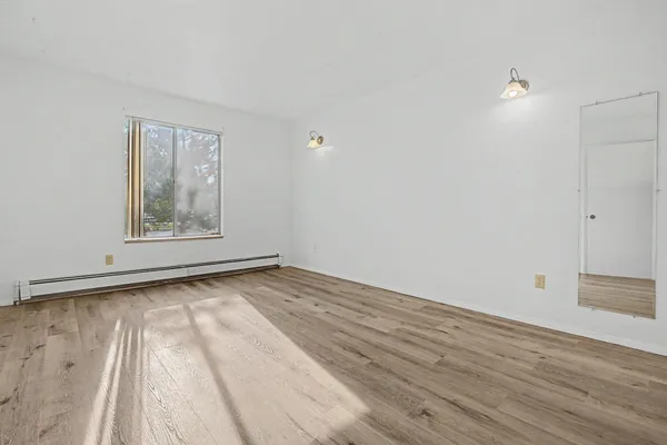 a view of an empty room with wooden floor and a window