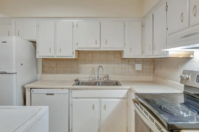 a kitchen with stainless steel appliances granite countertop a sink stove refrigerator and cabinets