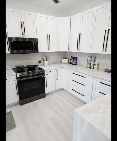 a kitchen with granite countertop white cabinets and stainless steel appliances