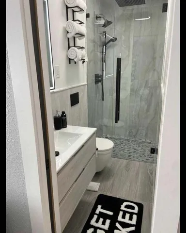 a bathroom with a sink a toilet a mirror and shower