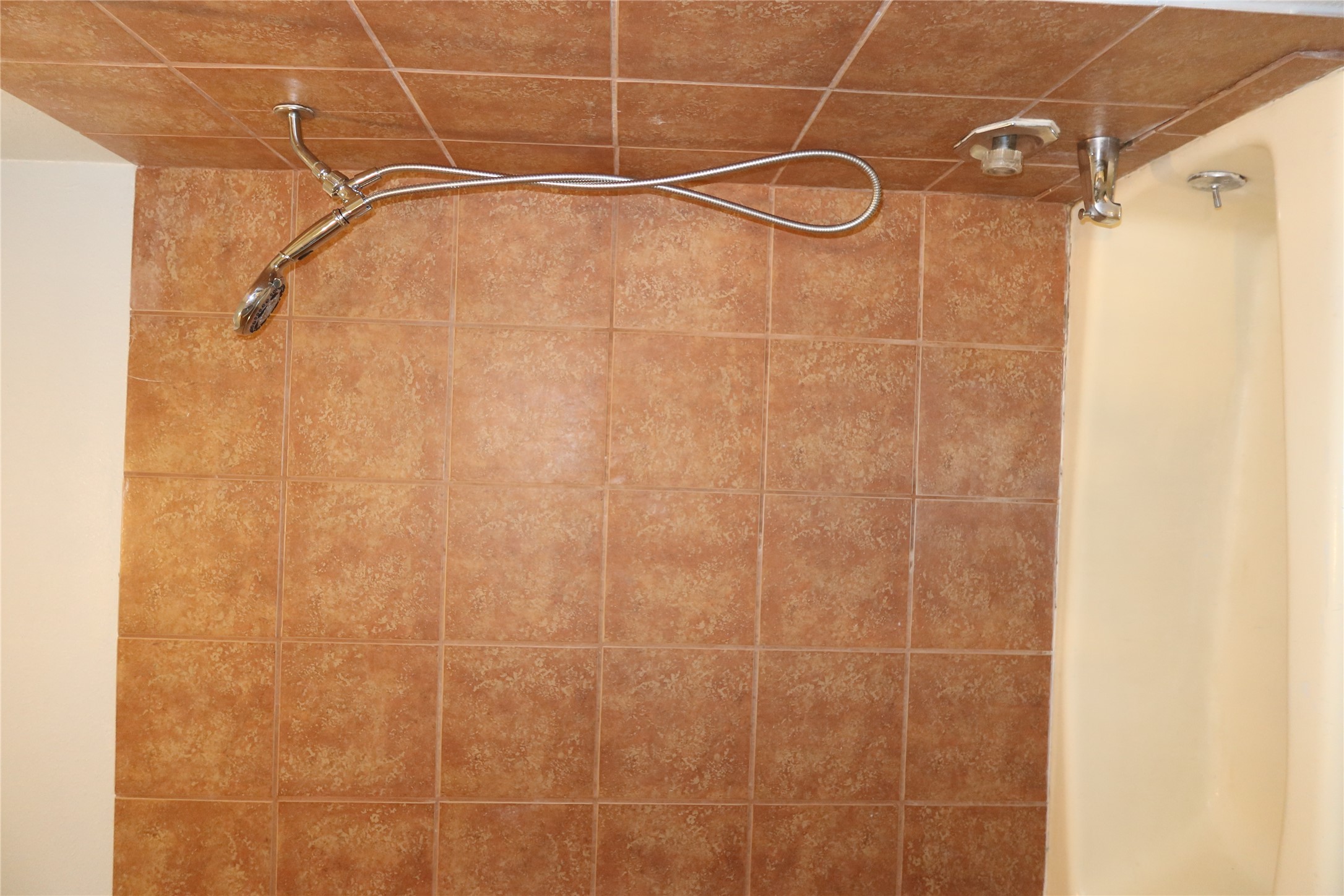 2802 Nueces Street, Unit 306 Austin, TX 78705 - Photo 11 of 20 Tub and shower combination featuring earth-toned ceramic tile surround, handheld shower fixture, and polished chrome hardware
