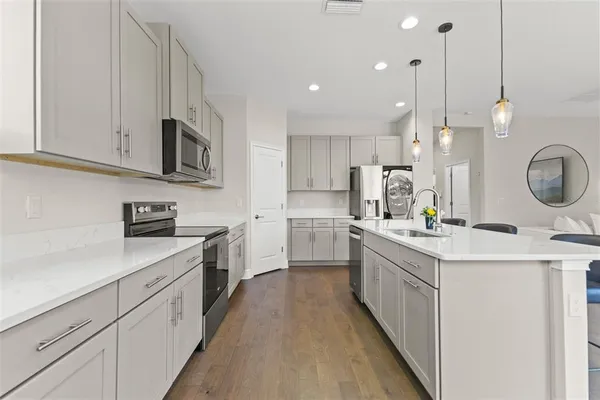 a kitchen with kitchen island granite countertop a sink a stove oven a counter space and cabinets