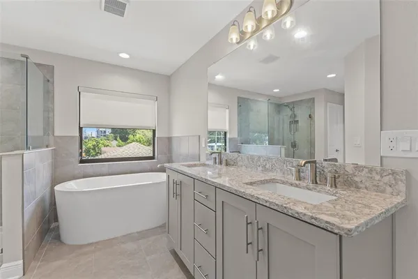 a bathroom with a granite countertop sink a large mirror and a bathtub