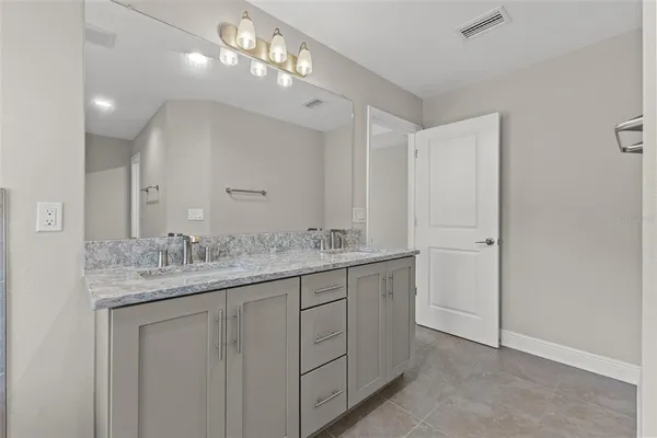 a bathroom with a granite countertop double vanity sink and a mirror