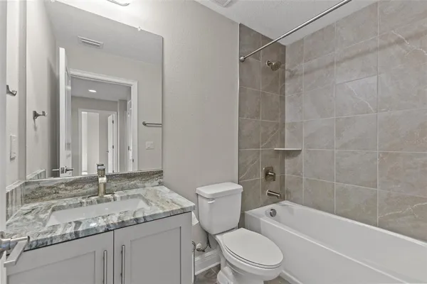 a bathroom with a granite countertop sink toilet and shower