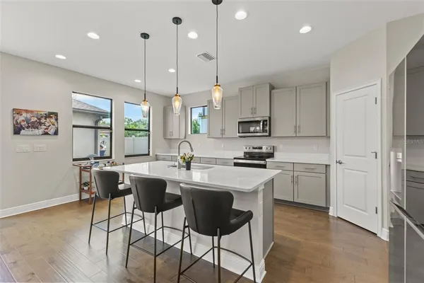 a kitchen with stainless steel appliances granite countertop a sink a stove a refrigerator cabinets and chairs