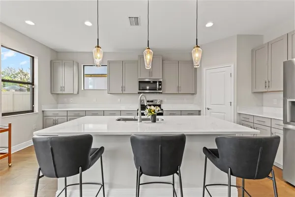 a kitchen with stainless steel appliances kitchen island granite countertop a sink a microwave a counter and chairs