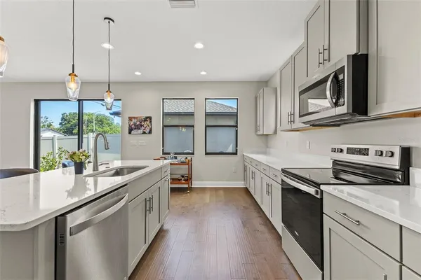 a kitchen with stainless steel appliances granite countertop a sink a stove and a wooden floors