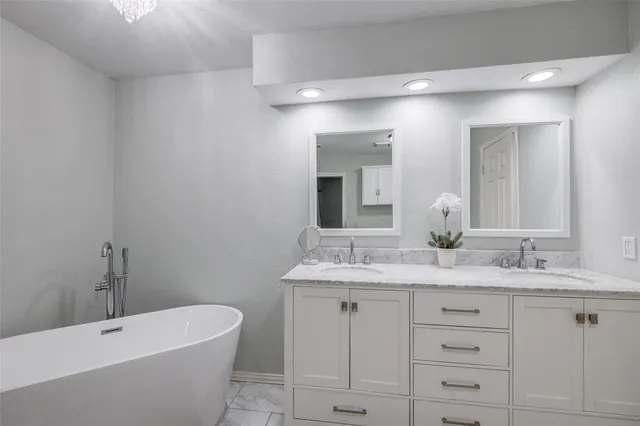 a bathroom with a granite countertop sink mirror and bathtub