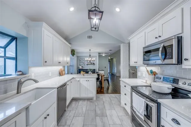a kitchen with stainless steel appliances granite countertop a sink dishwasher stove refrigerator and cabinets