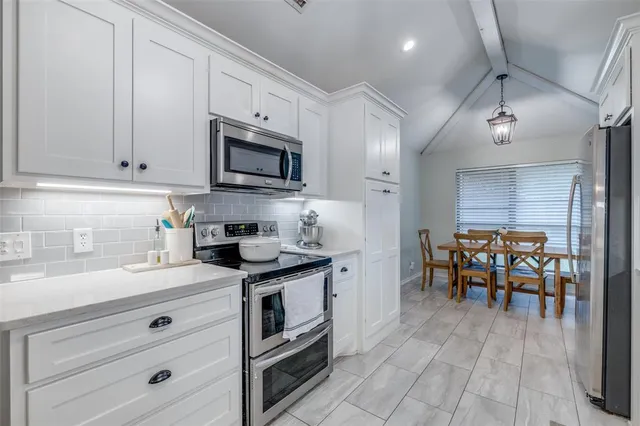 a kitchen with stainless steel appliances granite countertop a stove a sink dishwasher and a refrigerator with wooden cabinets