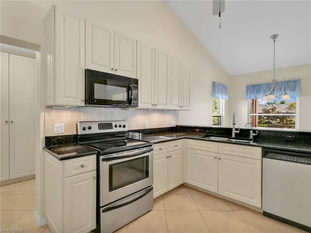 a kitchen with granite countertop white cabinets and appliances