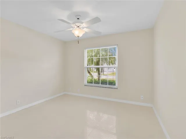 an empty room with a fan & a ceiling fan