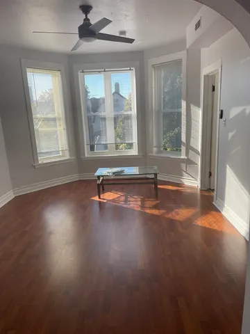 a view of empty room with wooden floor and fan