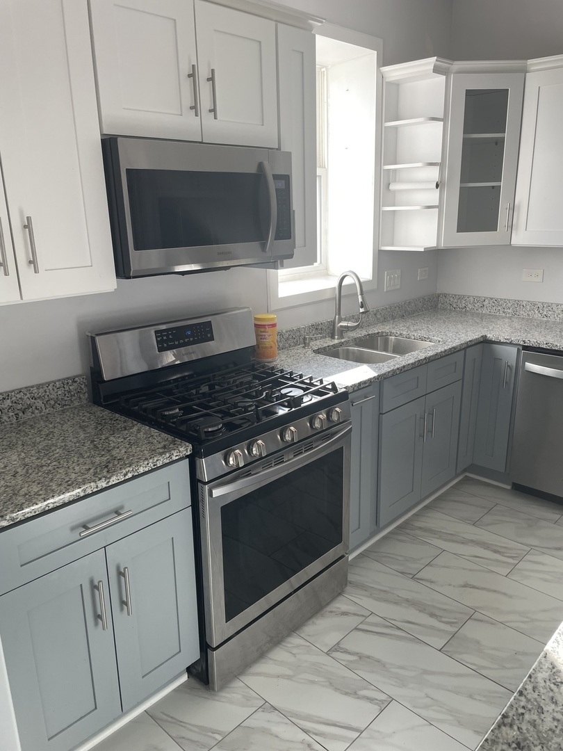 1511 North Keystone Avenue, Unit 2 Chicago, IL 60651 - Photo 4 of 8 a kitchen with stainless steel appliances granite countertop a stove microwave and sink