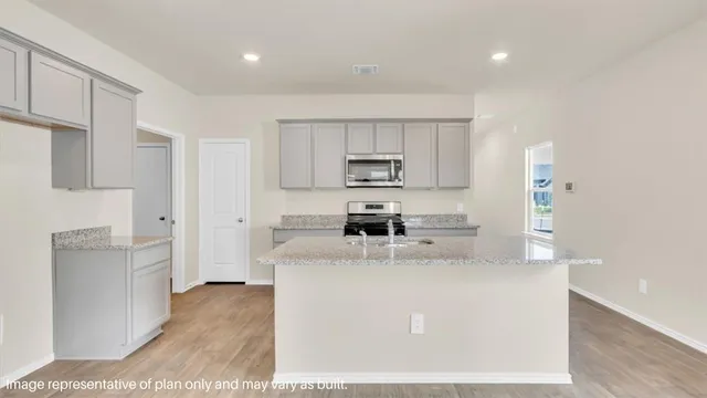 a kitchen with stainless steel appliances granite countertop a sink a stove a refrigerator a center island and cabinets