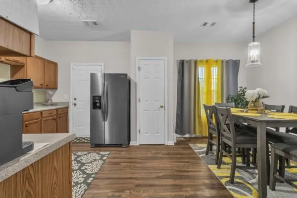 a kitchen with stainless steel appliances granite countertop a refrigerator a stove and a dining table with wooden floor