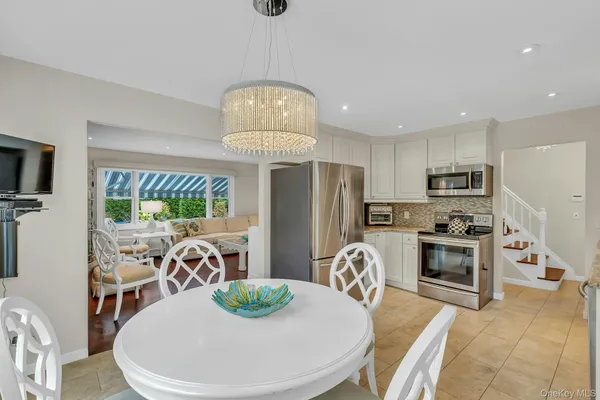 a view of a dining room with furniture a kitchen and chandelier