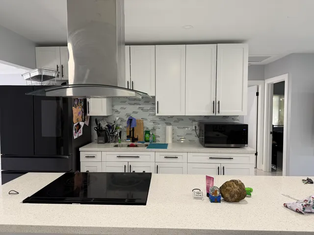 a kitchen with stainless steel appliances kitchen island granite countertop a sink a stove and a microwave