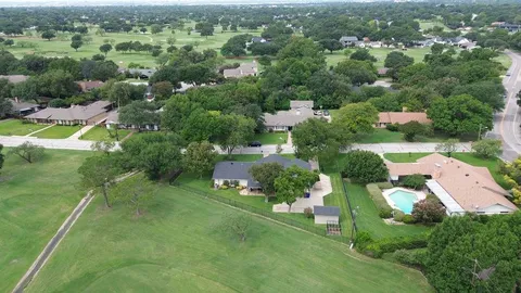 an aerial view of residential houses with outdoor space and trees