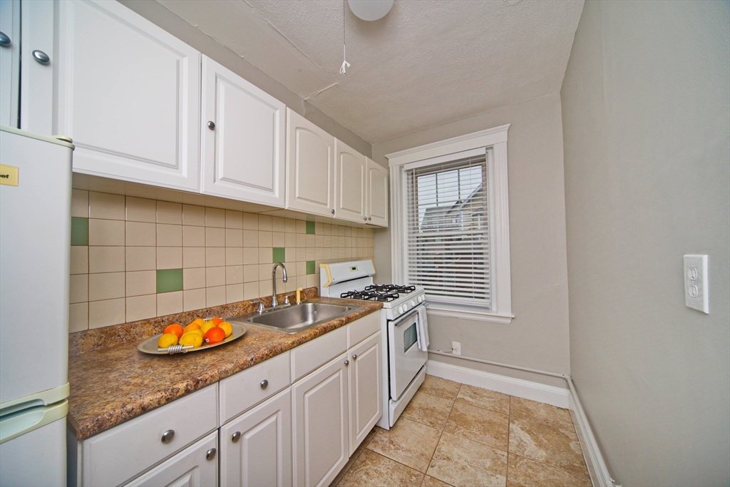 68 Linden Street, Unit 27 Everett, MA 02149 - Photo 9 of 13 a kitchen with granite countertop a sink a white cabinets and a window