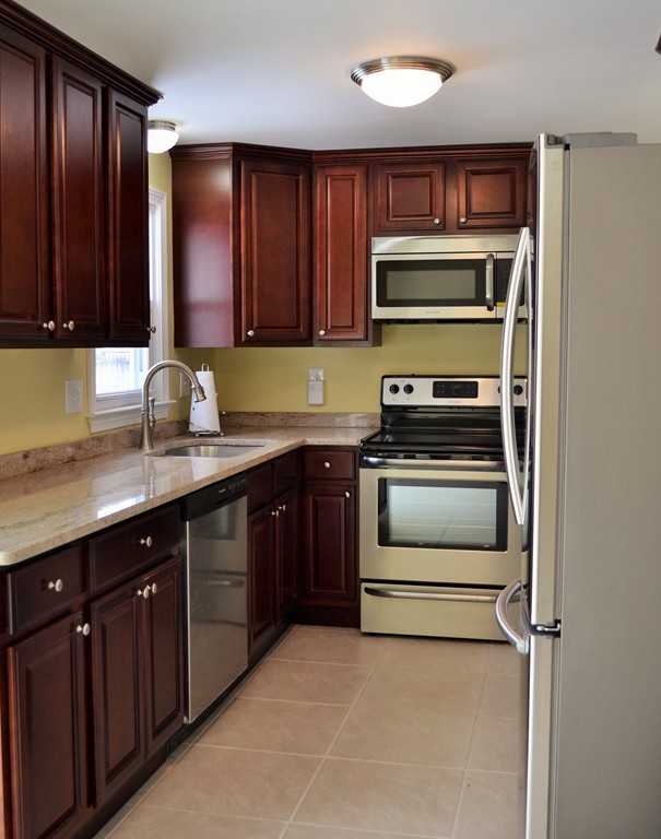 29 East Hill Road Springfield, MA 01109 - Photo 4 of 19 a kitchen with granite countertop wooden cabinets a stove top oven a sink and dishwasher