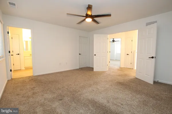 an empty room with closet and a ceiling fan