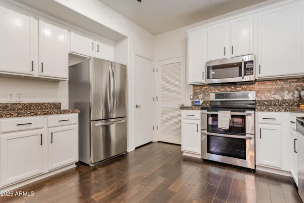 a kitchen with stainless steel appliances and wooden floor