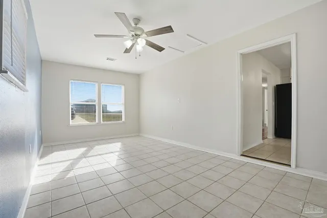 a view of an empty room with window and chandelier fan