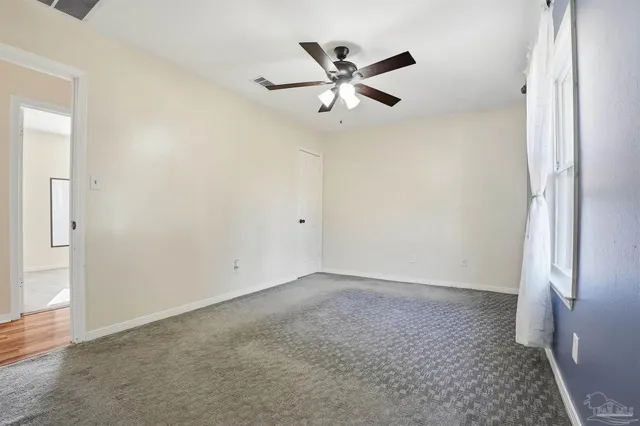 an empty room with windows and fan