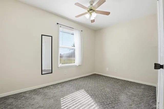 an empty room with windows and fan