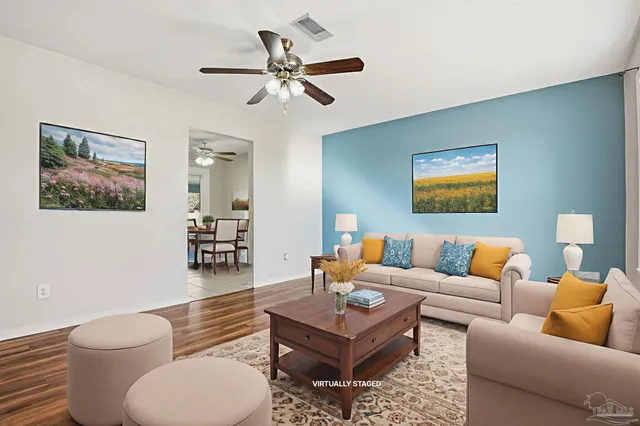 a living room with furniture a rug and a ceiling fan