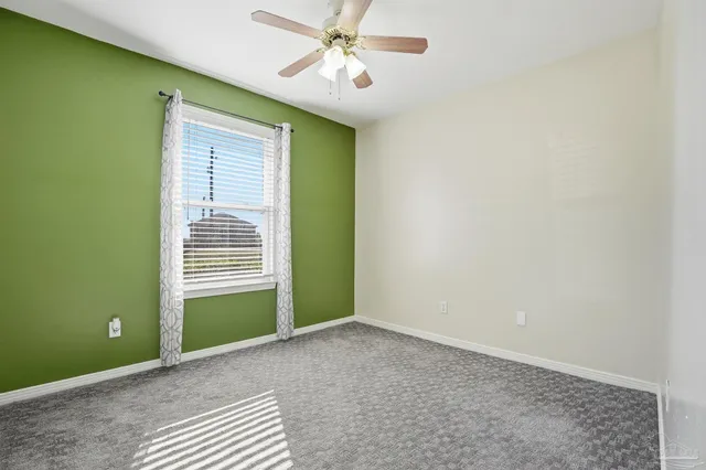 a view of an empty room with a window and a ceiling fan