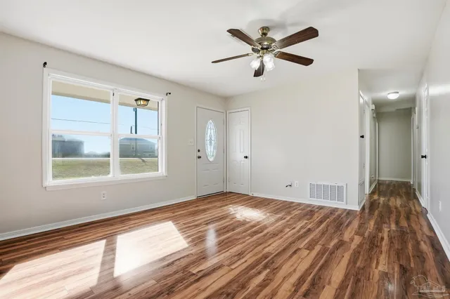a view of empty room with wooden floor and fan