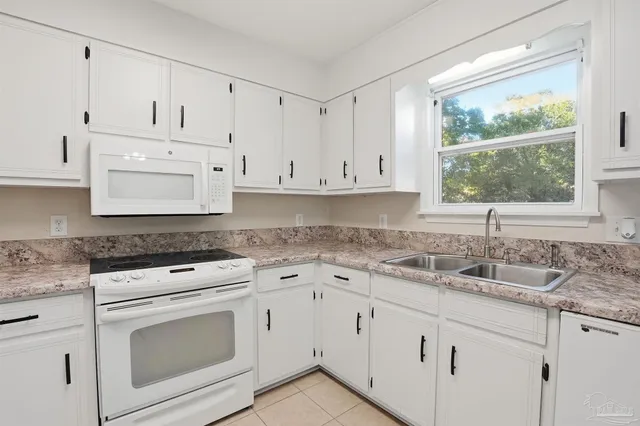 a kitchen with granite countertop white cabinets and white appliances