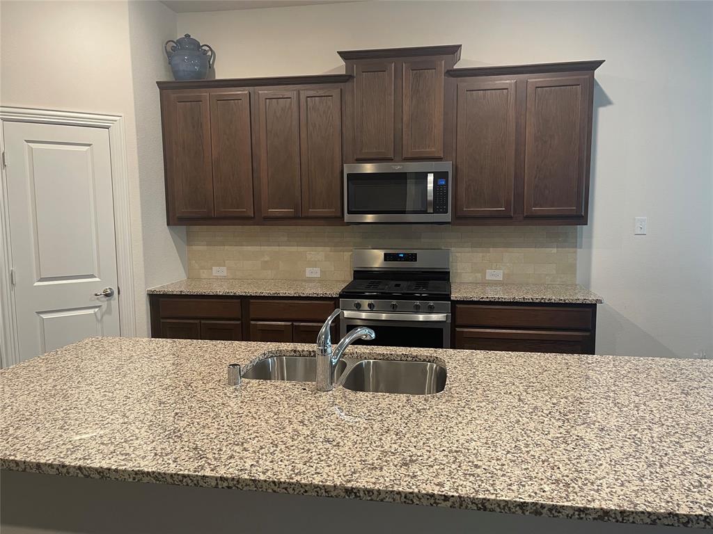 4111 Beamer Drive Forney, TX 75126 - Photo 4 of 25 a kitchen with kitchen island granite countertop a sink stove and microwave