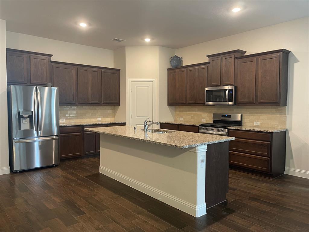 4111 Beamer Drive Forney, TX 75126 - Photo 8 of 25 a kitchen with stainless steel appliances wooden cabinets sink and microwave