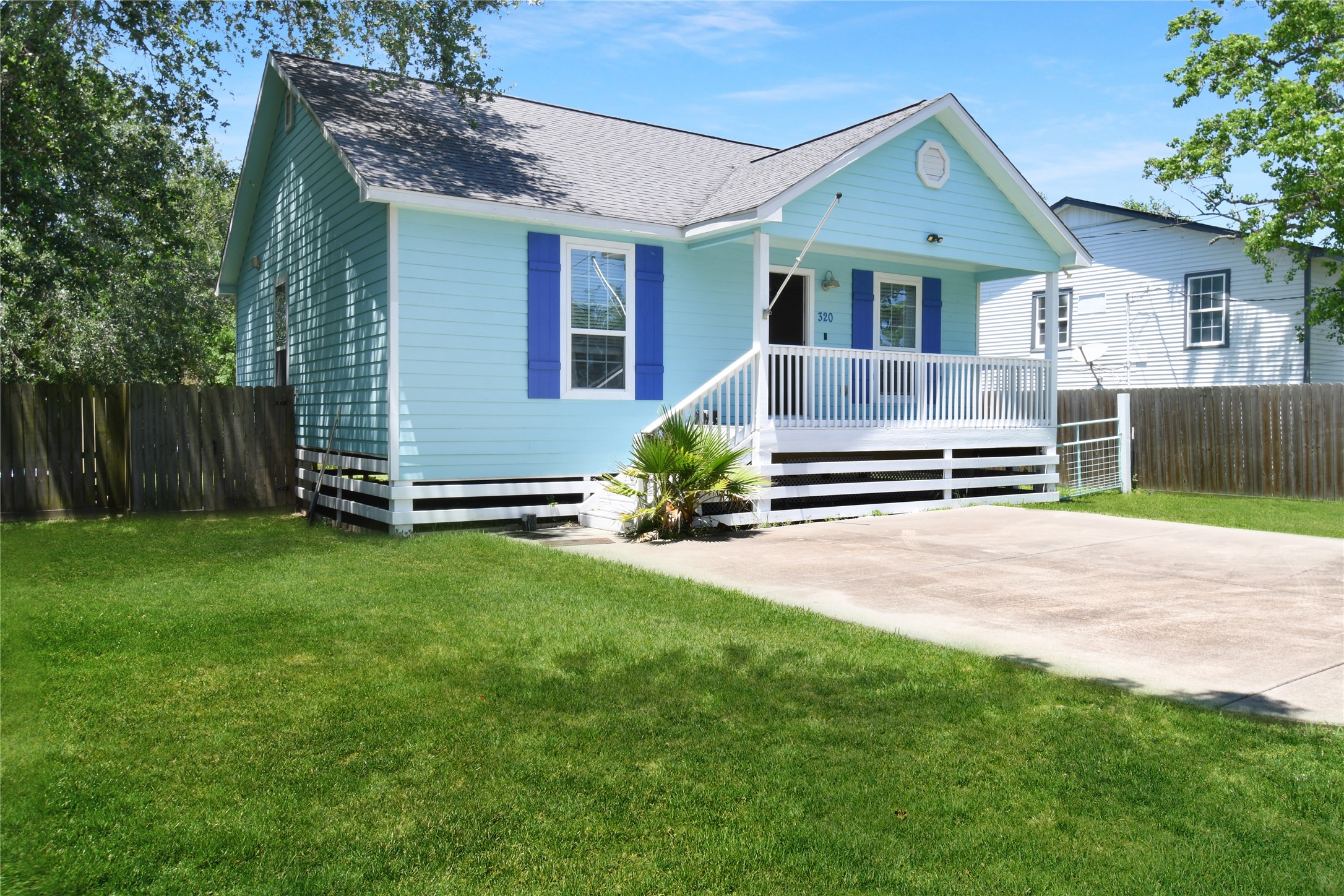 320 10th Street Dickinson, TX 77539 - Photo 2 of 21 Charming corner-view home with a welcoming front porch, vibrant blue accents, and a spacious, lush lawn perfect for family living.