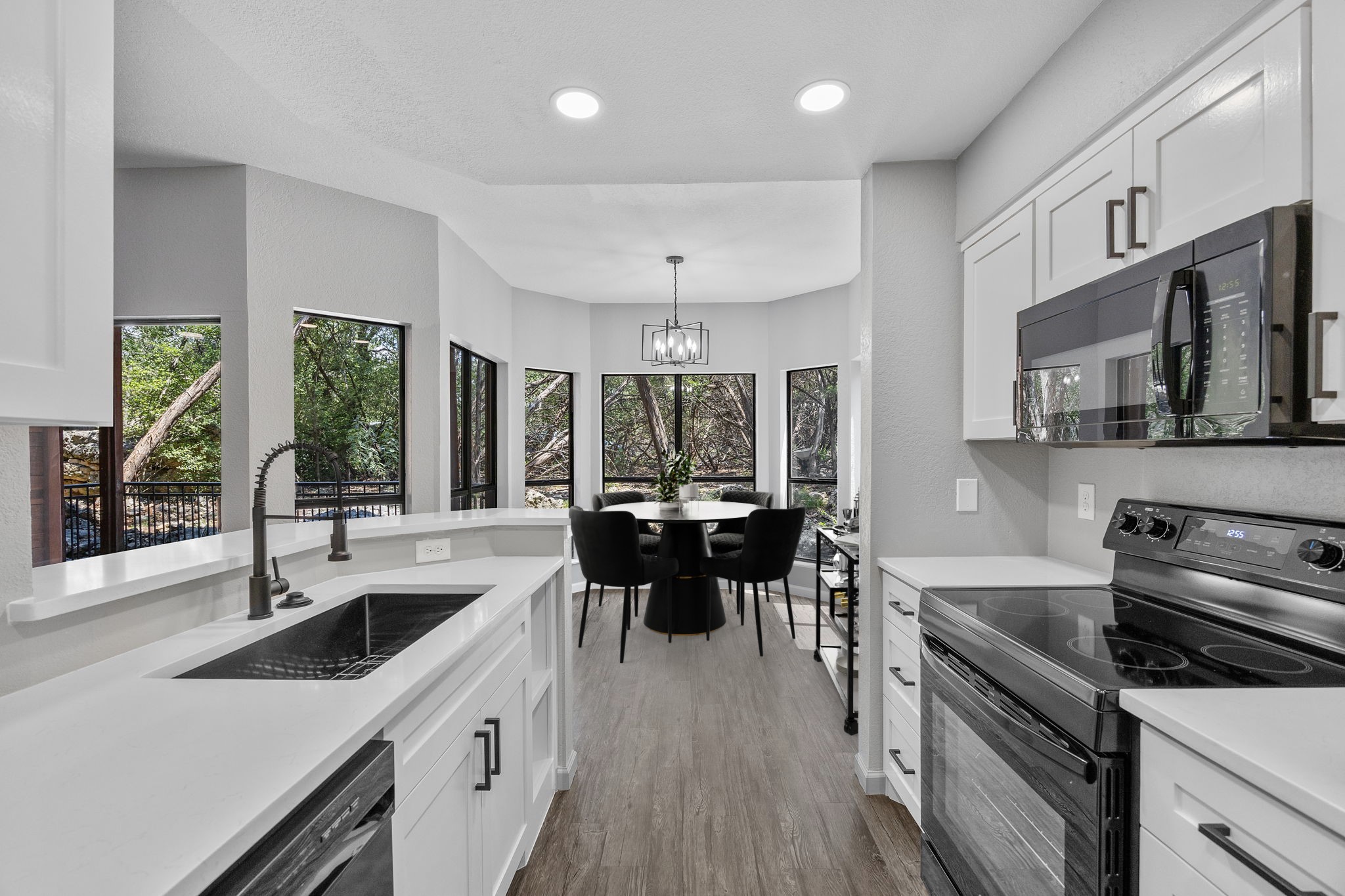 4711 Spicewood Springs Road, Unit 1106 Austin, TX 78759 - Photo 5 of 19 Modern kitchen featuring white shaker cabinetry, light-toned countertops, and black appliances